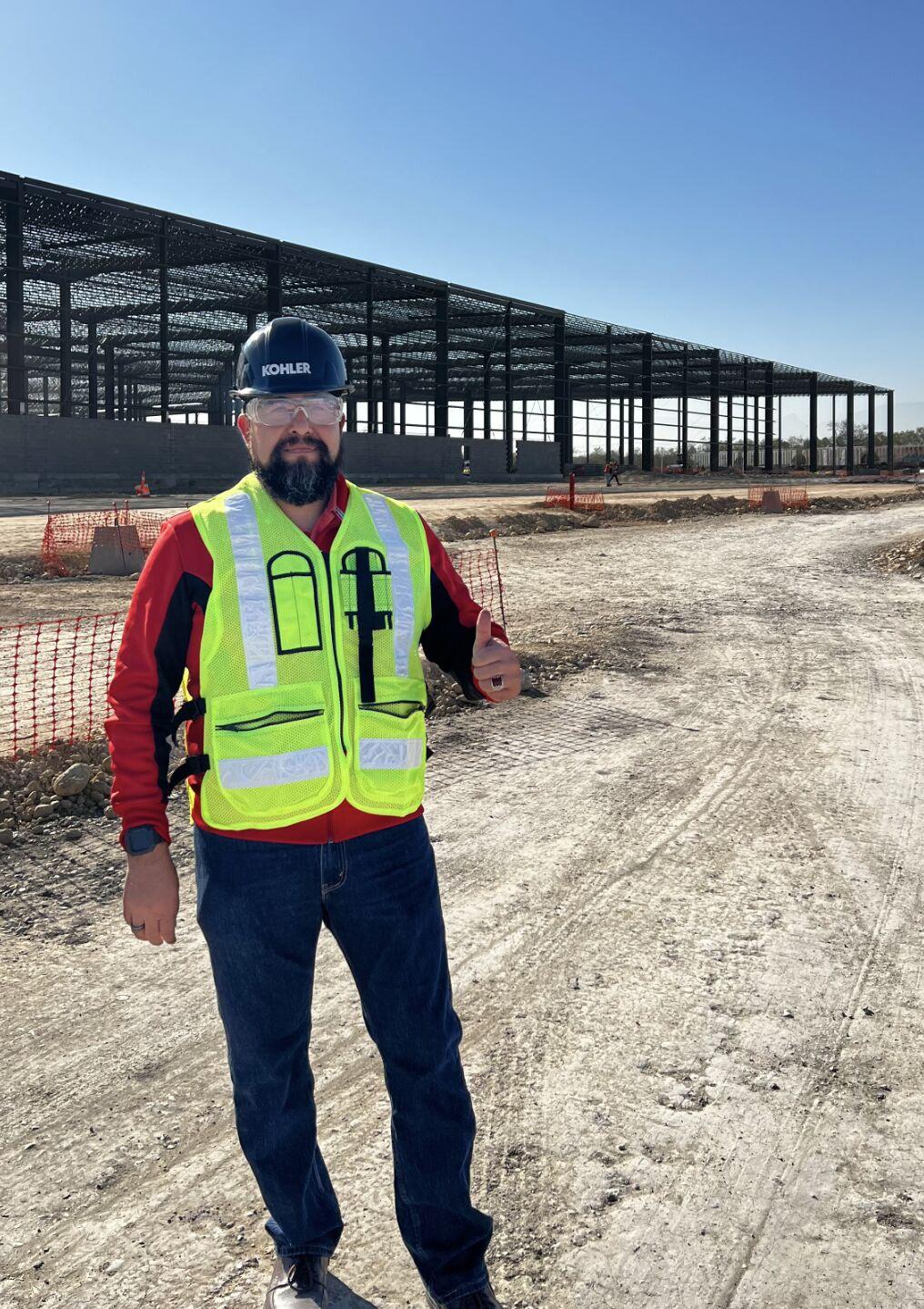 Person standing outside in hard hat and reflective vest