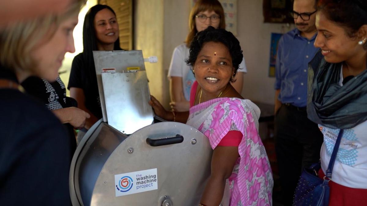 people smiling around a washing machine