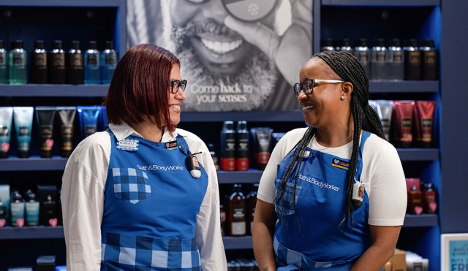 Two Bath & Body Works employees smiling at each other in a store