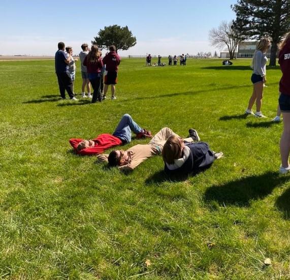 Three people lying on the grass looking up