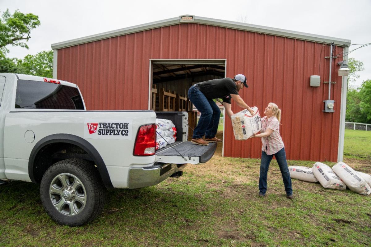 A man helping a woman unload product from a Tractor Supply truck