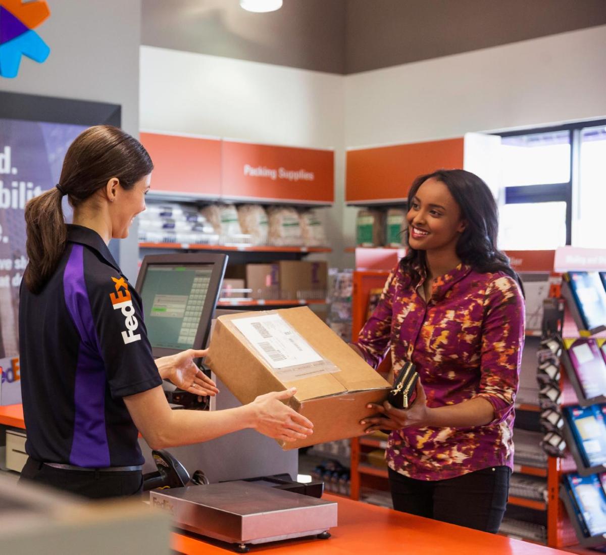 FedEx employee hands box to smiling customer