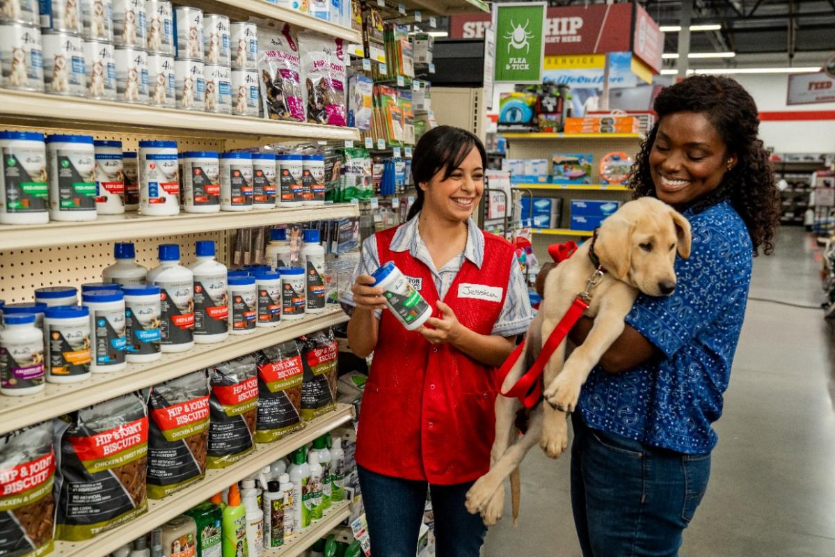 Tractor Supply employee helping a customer who is holding her dog