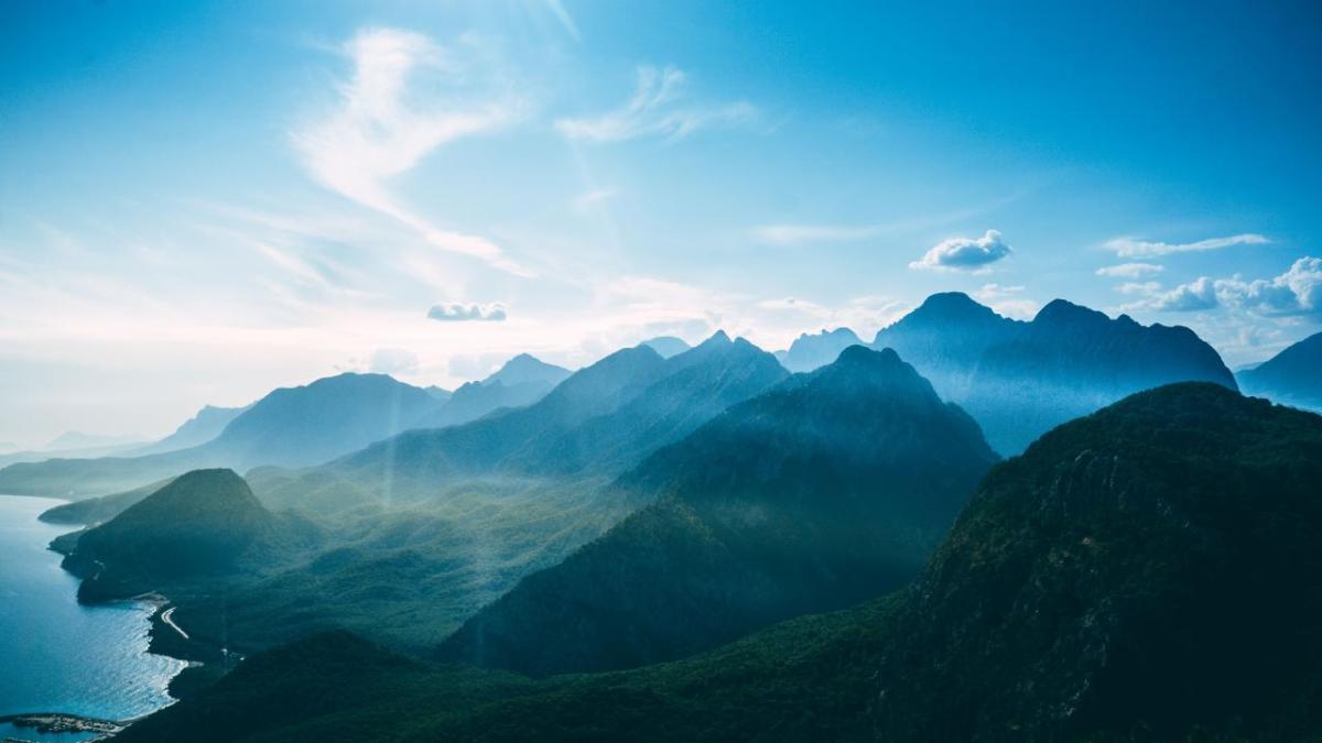 Aerial view of a mountain landscape with blue sky behind.