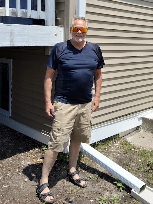 Mark shown in front of his home.