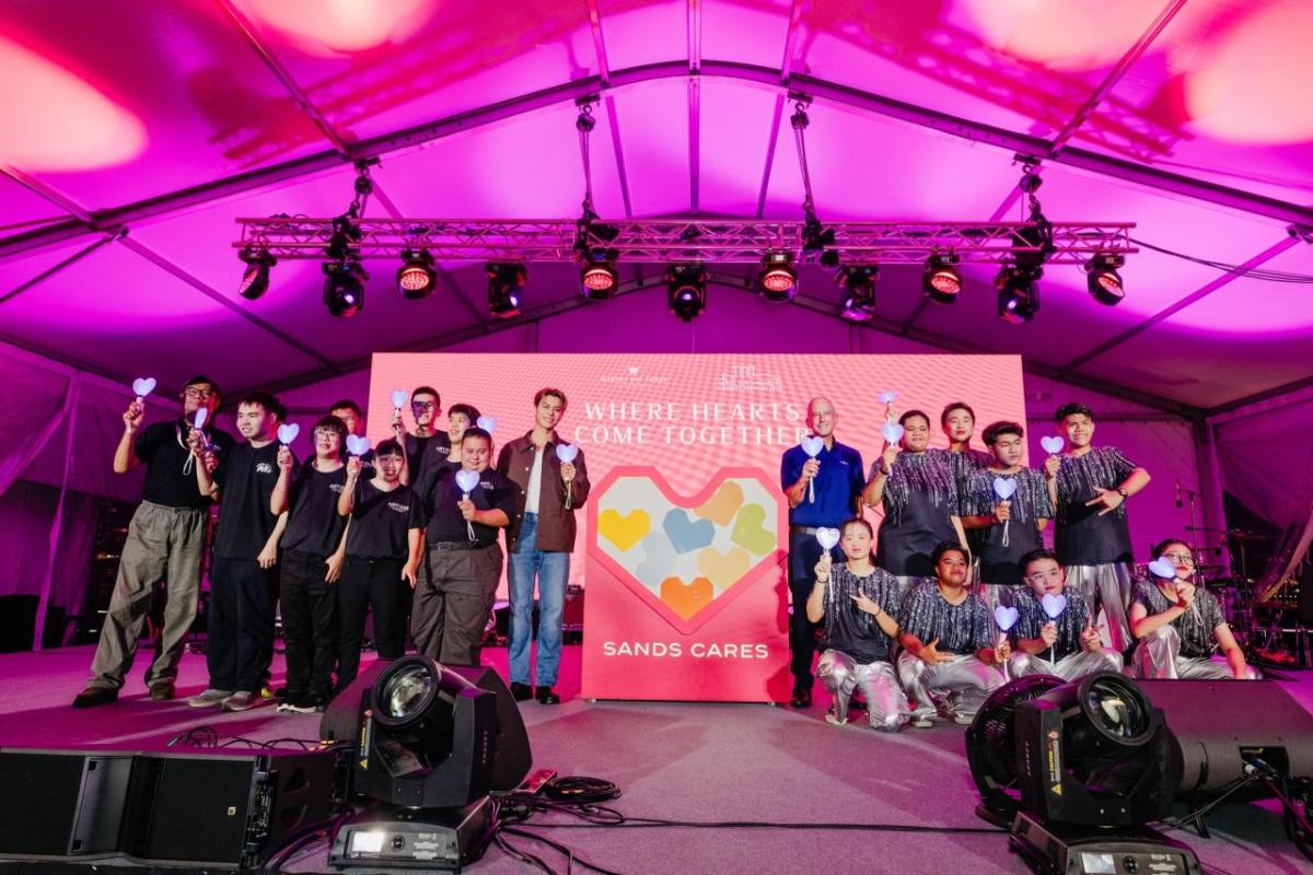 People posing on a stage, holding up a heart