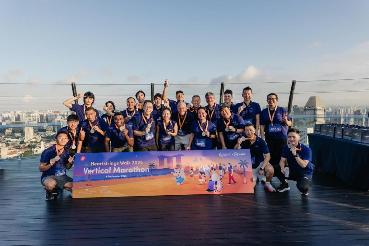 A group posing on the flat top of a building with the view of a city behind them