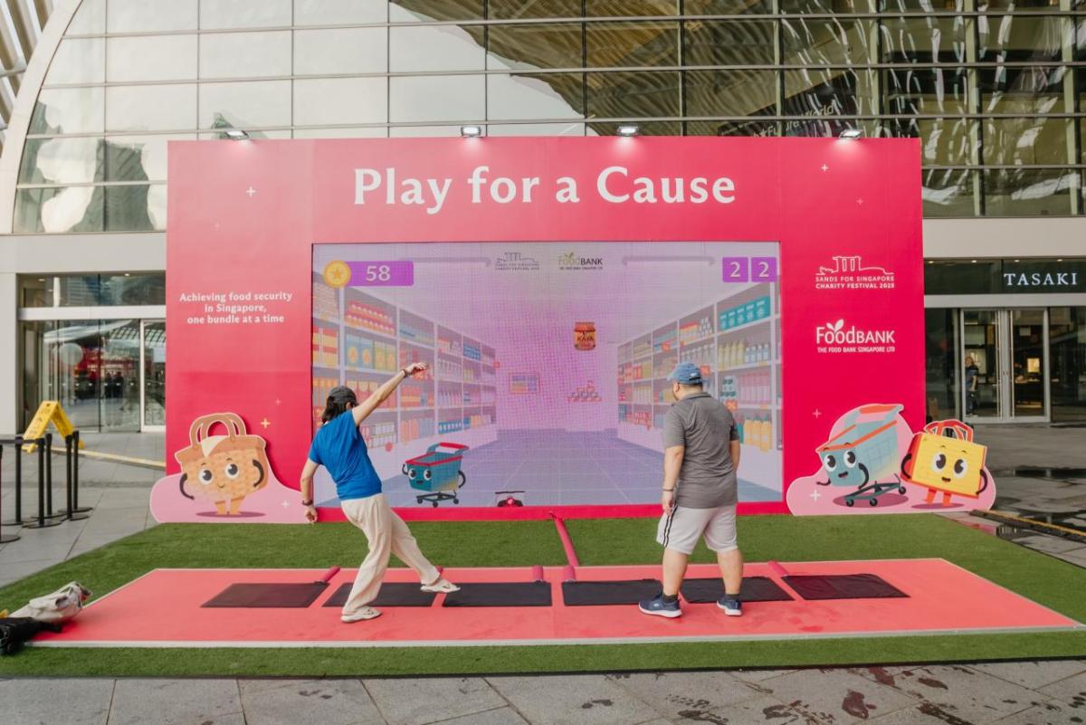 Two adults playing in front of a "Play for a Cause" sign