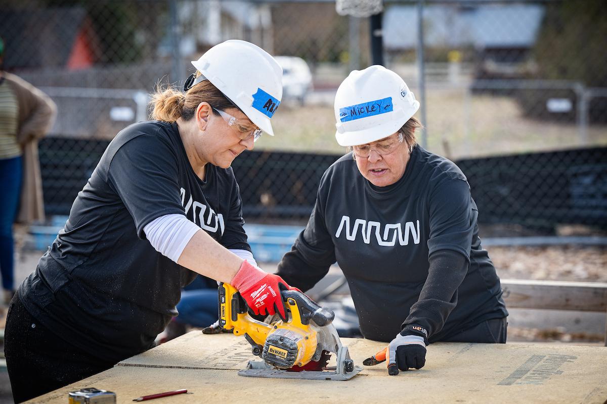 2 arrow employees using a saw