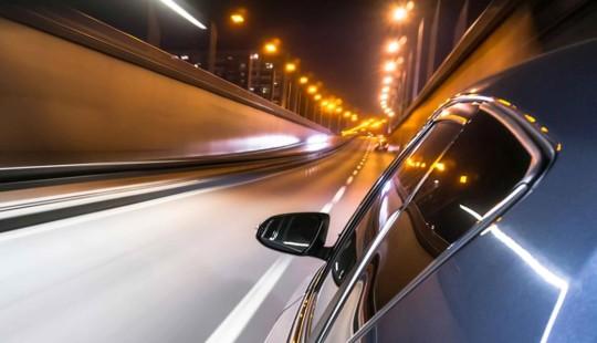 the side of a car driving at night with streetlights above