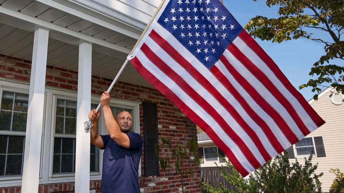 person putting American flag on house