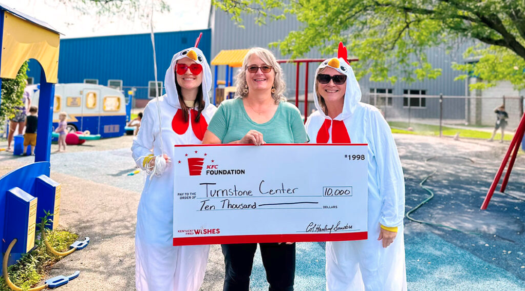 Three people posing with an oversized check