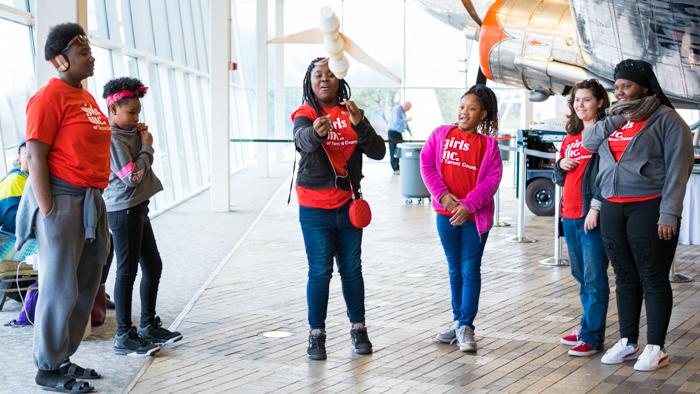 Girls watch a paper plane fly