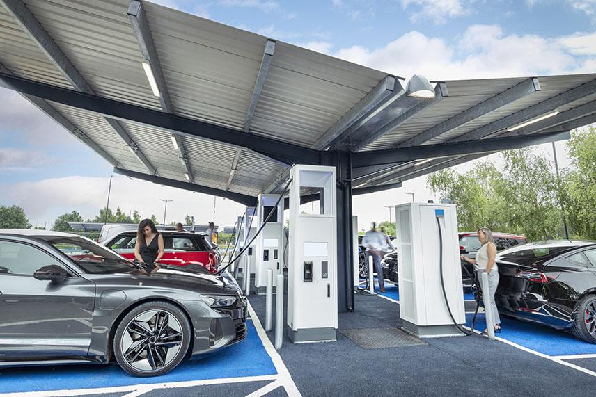 Electric Vehicle charging station shown. A person is charging a vehicle.