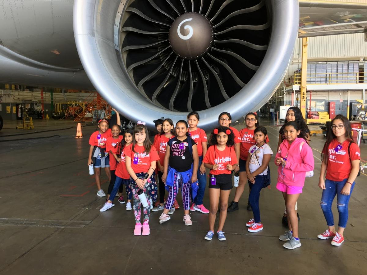 Class of girls in front of jet engine