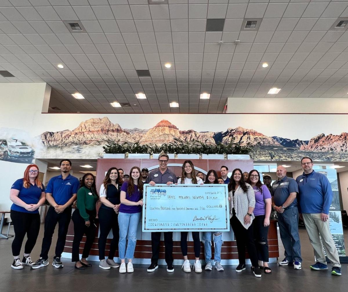 People posing together, holding a large check