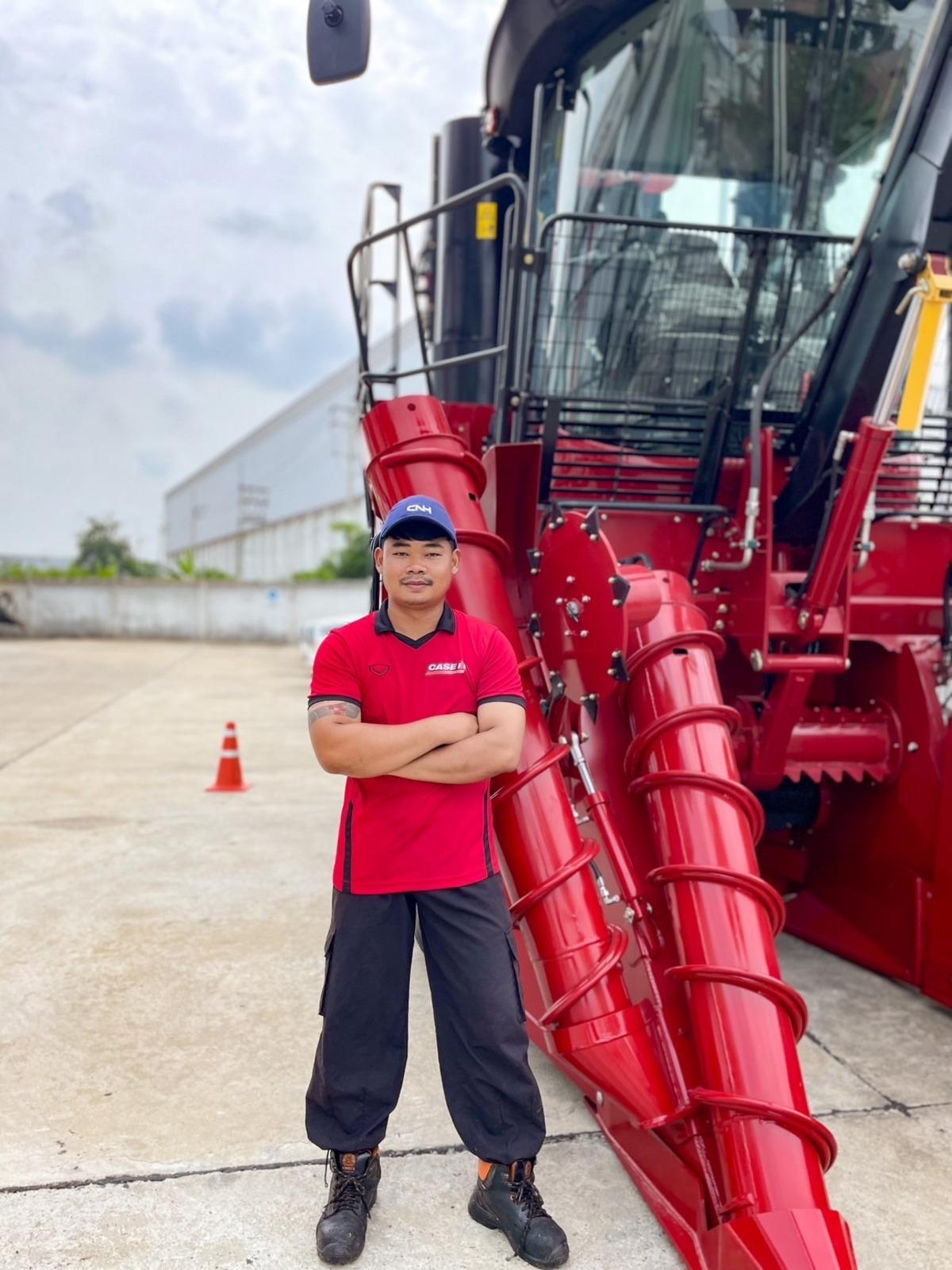 A person stood with their arms folded next agricultural machinery 