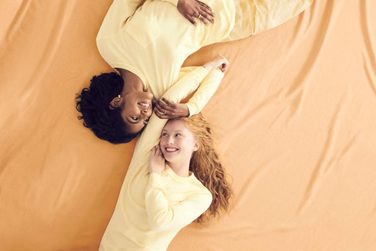 A Look into Comfort Colors’® Pigment Pure™ Dyeing Process with Product and Textile Leaders Two models wearing yellow Comfort Colors clothing, lying against a yellow backdrop