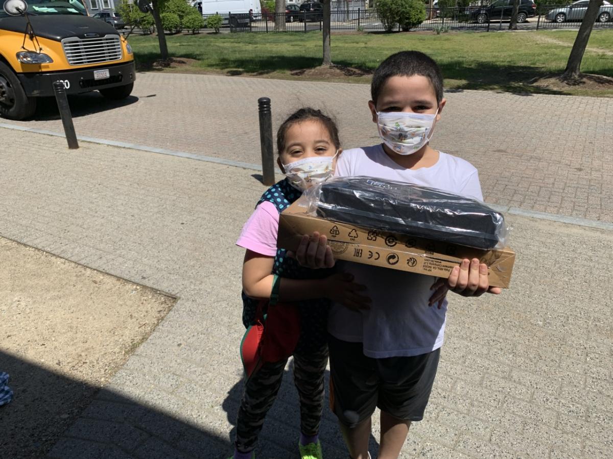 Kids holding computer box and supplies