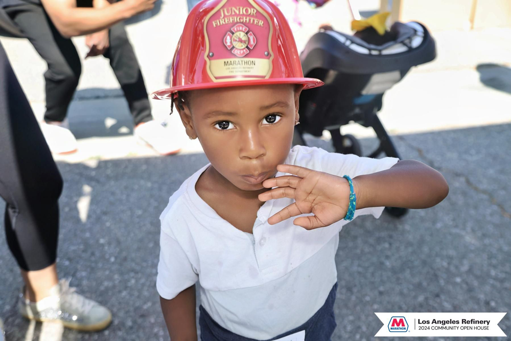 A child in a fire helmet waving to the camera