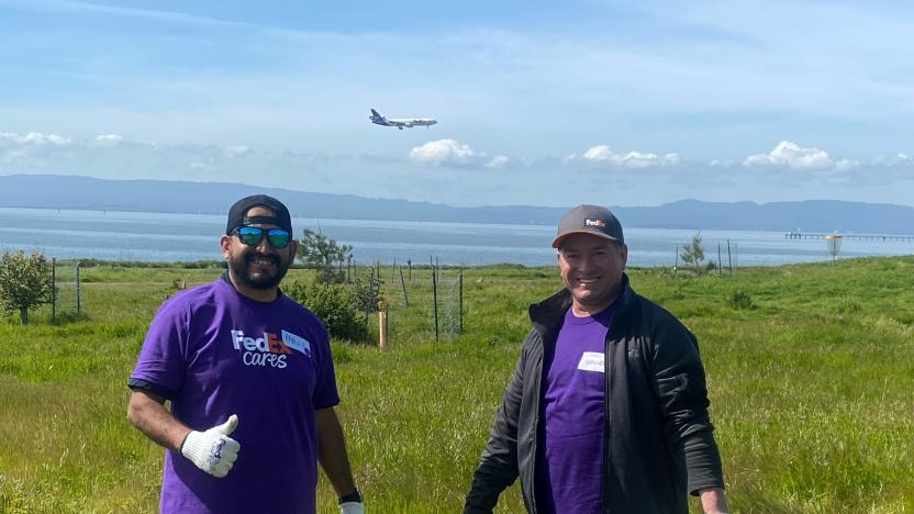 Two FedEx team members stood in a field