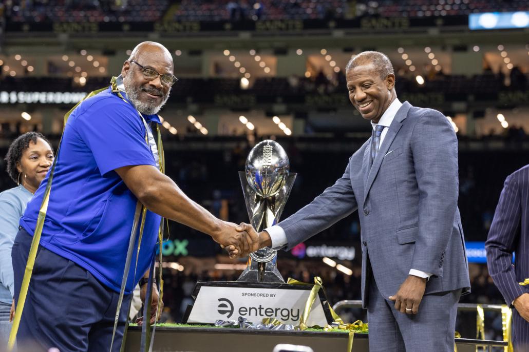 people shaking hands in front of a trophy