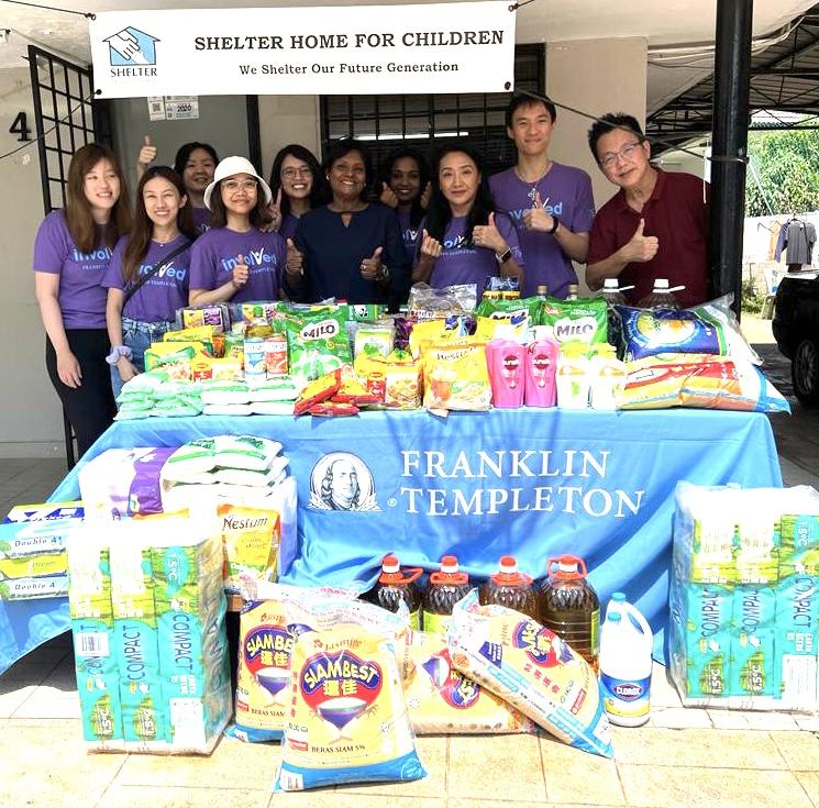 Group of Kuala Lumpur volunteers standing behind table piled with supplies