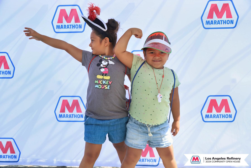 Two kids posing in front of a Marathon Petroleum banner