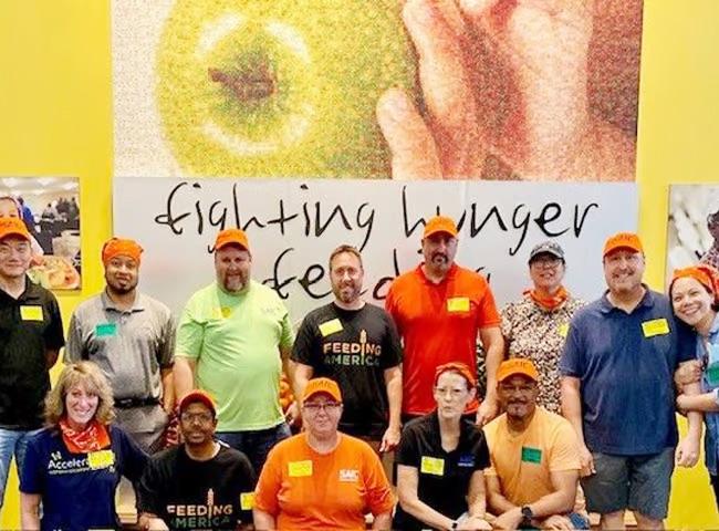 A group of people stood in front of a sign that reads 'fighting hunger feeding'