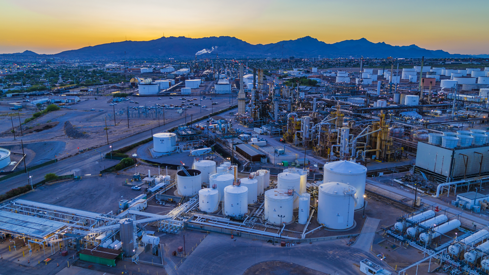 oil refinery in the desert at dawn, a mountain range on the horizon