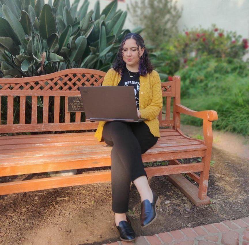 person sitting on a bench using a laptop