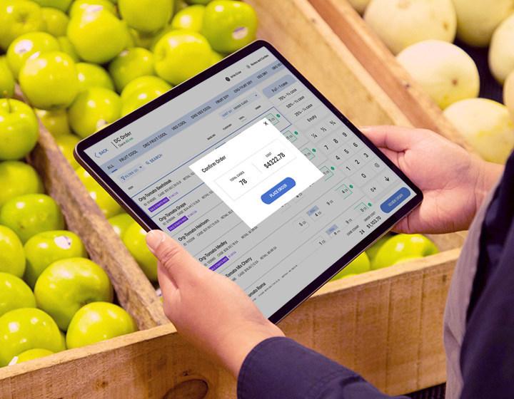Photo courtesy of Afresh: Afresh Technologies’ AI-powered predictive ordering and inventory solutions help reduce waste and offer the freshest product for customers person looking at a handheld computer screen