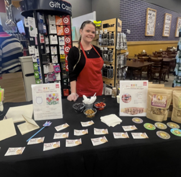 A person standing behind a table with food items