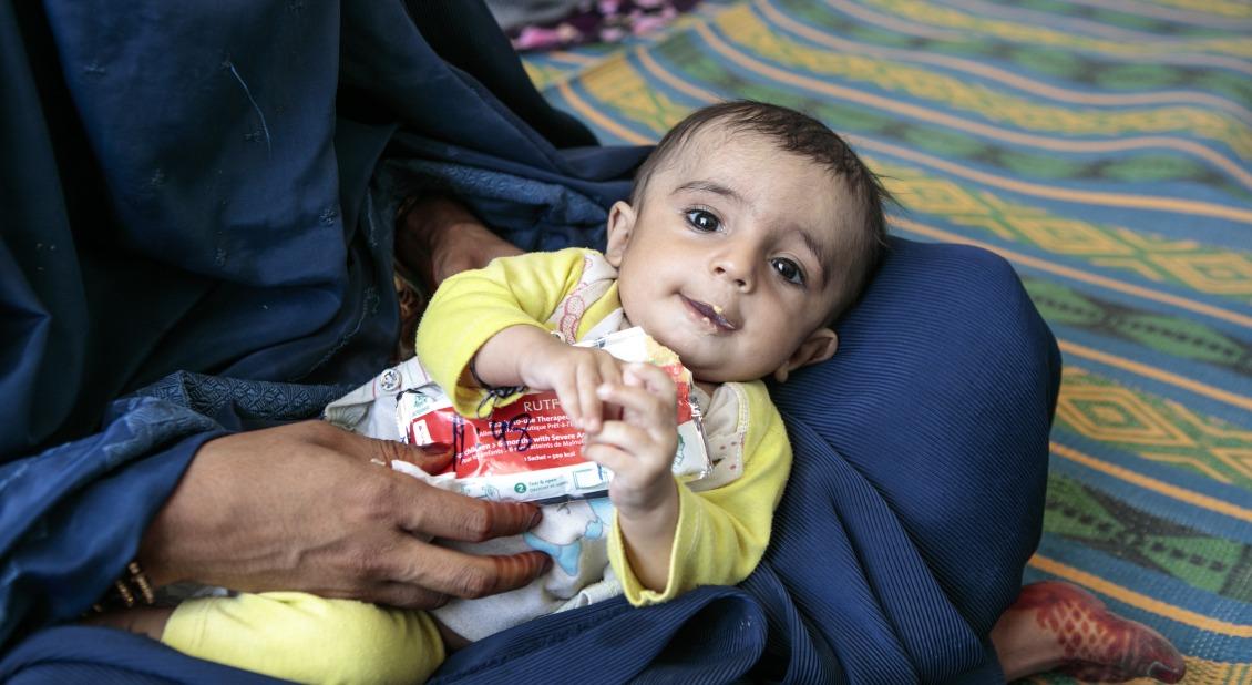 A young boy eats Plumpy'Nut, a peanut paste used to treat malnutrition, at one of Action Against Hunger's nutrition centers in Afghanistan's Helmand province. / Photo by Sandra Calligaro