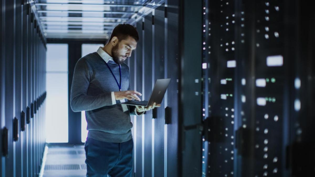 A man in a data center with a laptop.