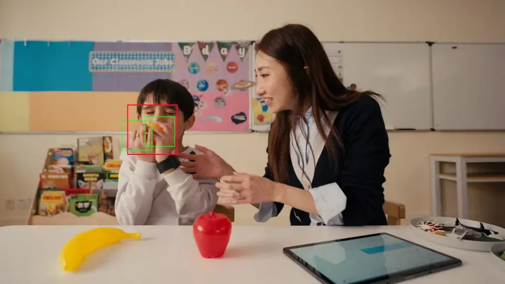 A child and a teacher sat at a desk in a classroom