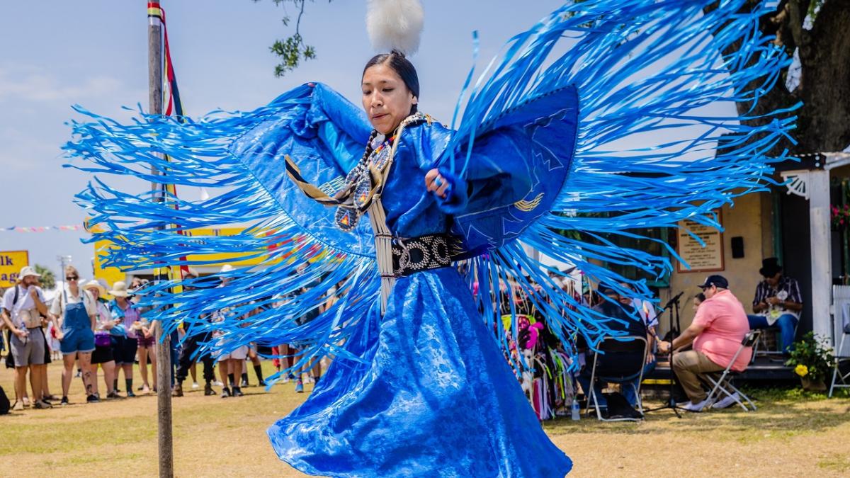 A person dancing in bright blue traditional dress.