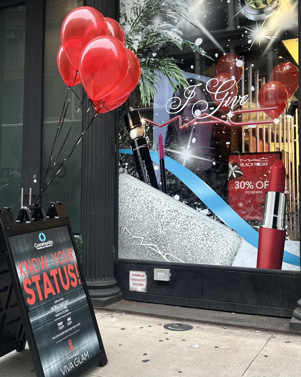 MAC store front with a "Know your status" board with red balloons in front.