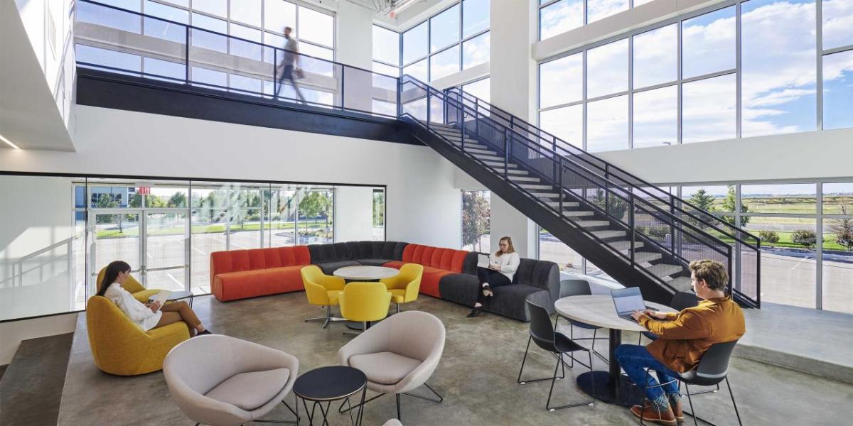 A lobby with people sat down on colourful seats and at a table