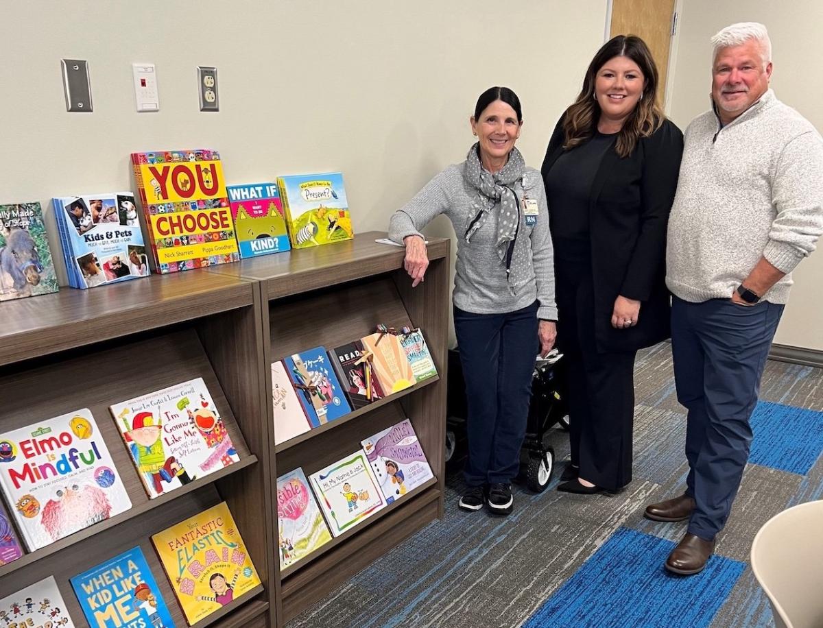 Sherry Iverson, director of patient and family support services at St. Luke's Children's Hospital; Jaime Gaudet; and Jason Gaudet visit the hospital’s Growing Minds Bookshelf.