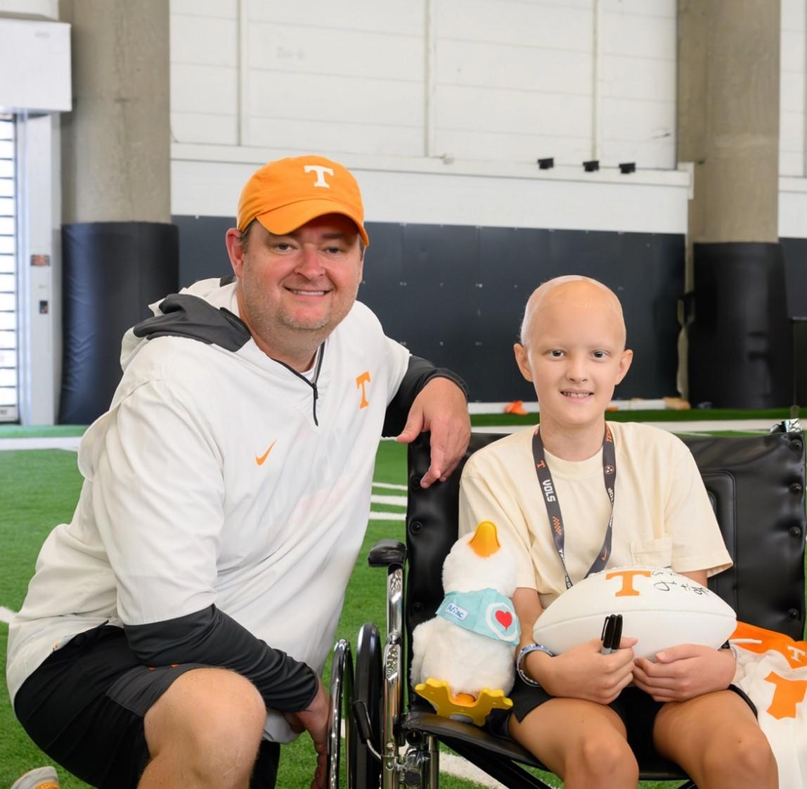 Tennessee Football Head Coach Josh Heupel presenting an Aflac My Special Duck and a football to a young patient.