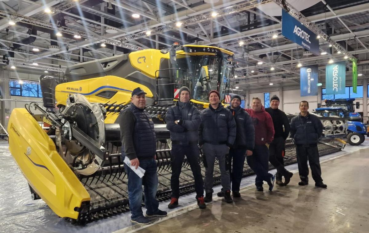 A group of people stood in front of yellow agricultural machinery 