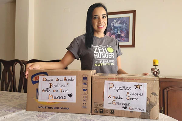 A person standing in a home, two boxes in front of them hand decorated with encouraging messages.