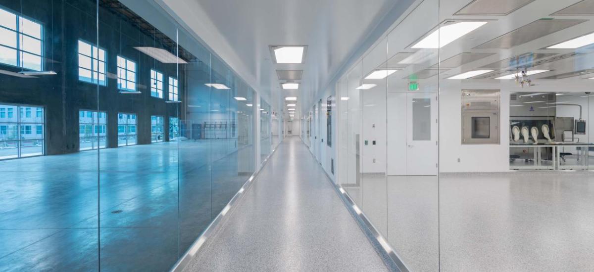 A long hallway with windowed walls, one side blue-tinted.