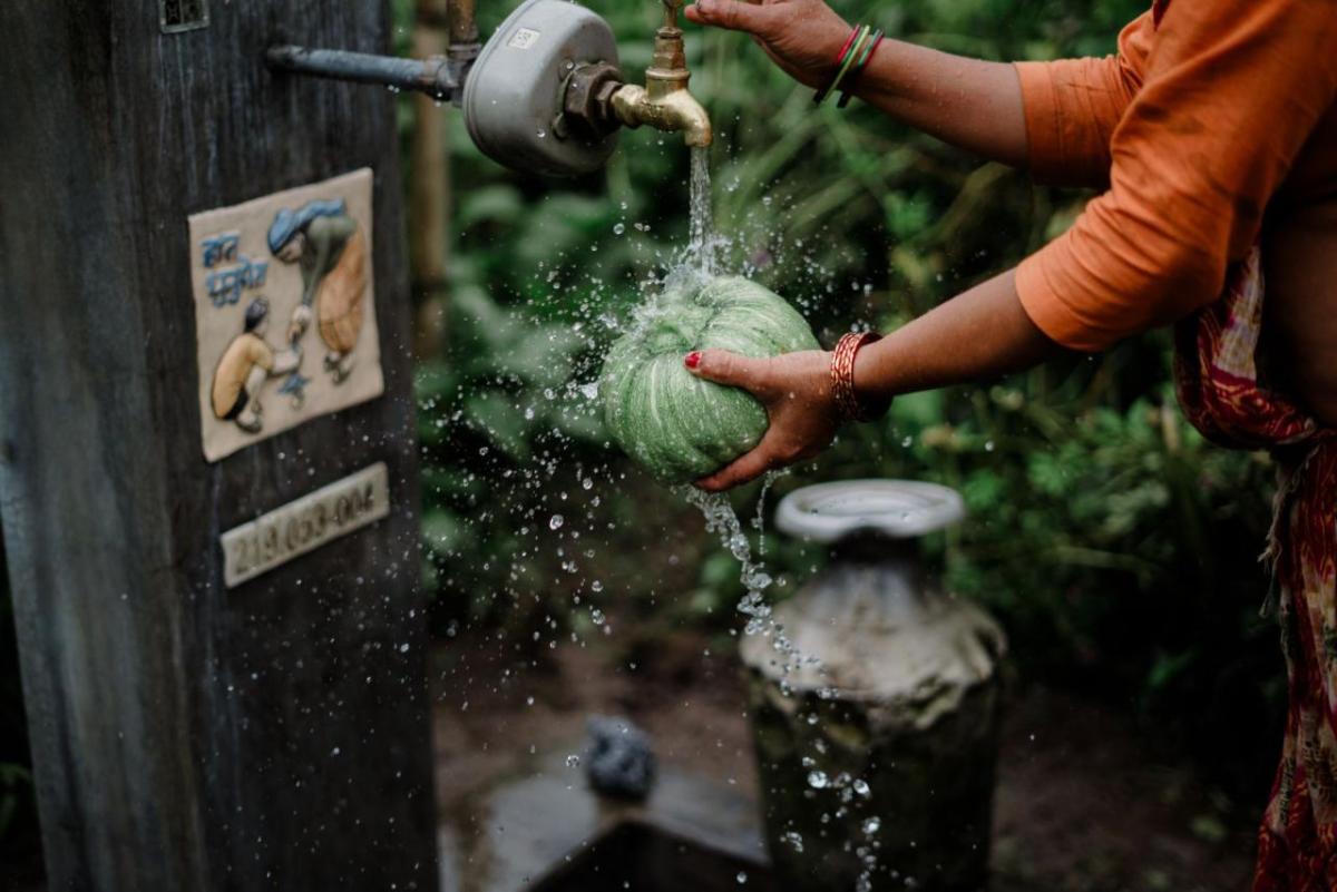 A woman uses a water well to wash a vegetable in Nepal