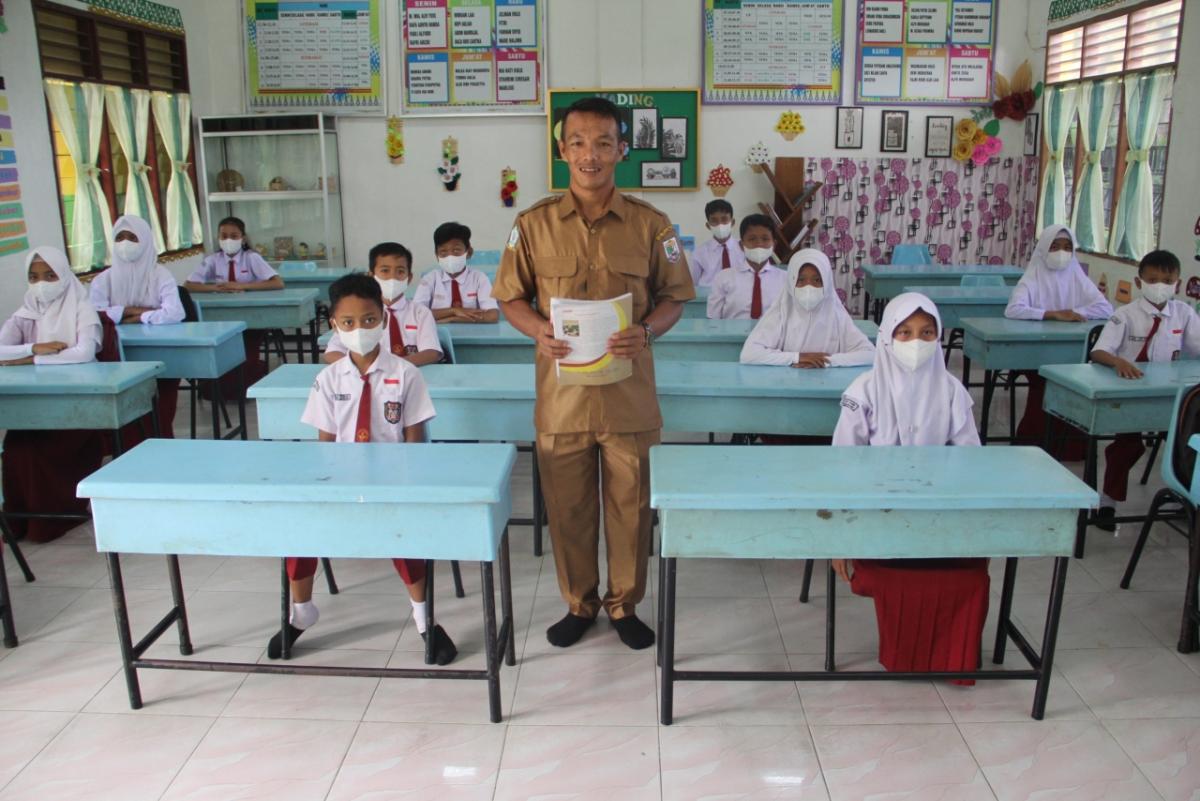 Teacher standing among students in desks