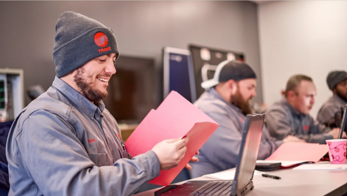People sitting at a desk with laptops and red folders