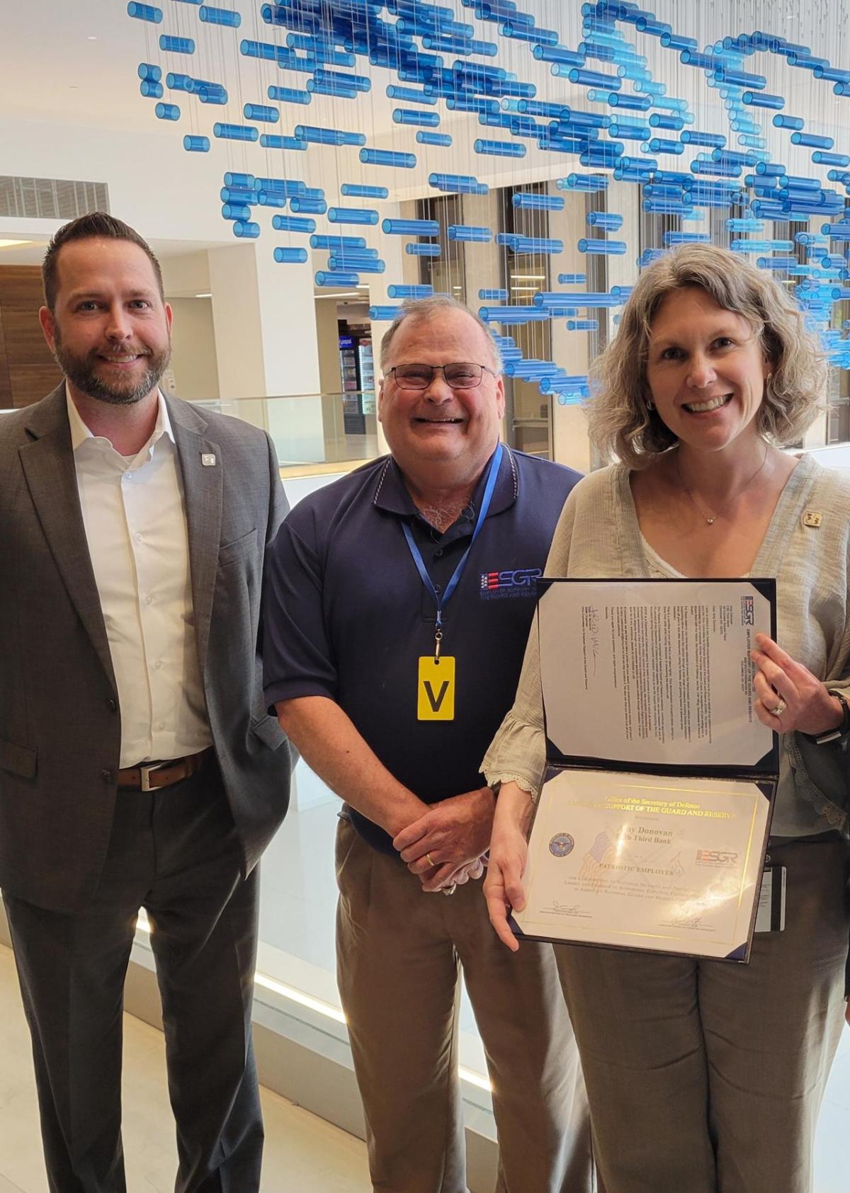 Joe Dunaway, a member of Fifth Third’s military business resource group (left), joins Mark Williams from the Employer Support of the Reserve and Guard to present Amy Donovan with the Patriot Award. As part of the award, Donovan and Dunaway will participate in a U.S. Air Force flight, which includes a refueling in the air. " "