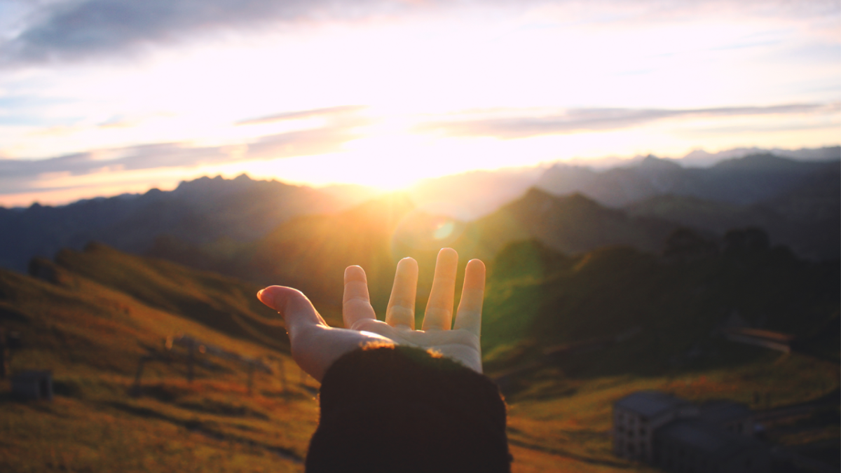 hand reaching out looking at sunrise