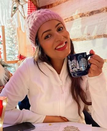 Ashwini seated and drinking a beverage. 